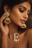 Fashion model gently touching her earrings, gold jhumka with blue stones and pearls shining under soft light, cinematic motion feel